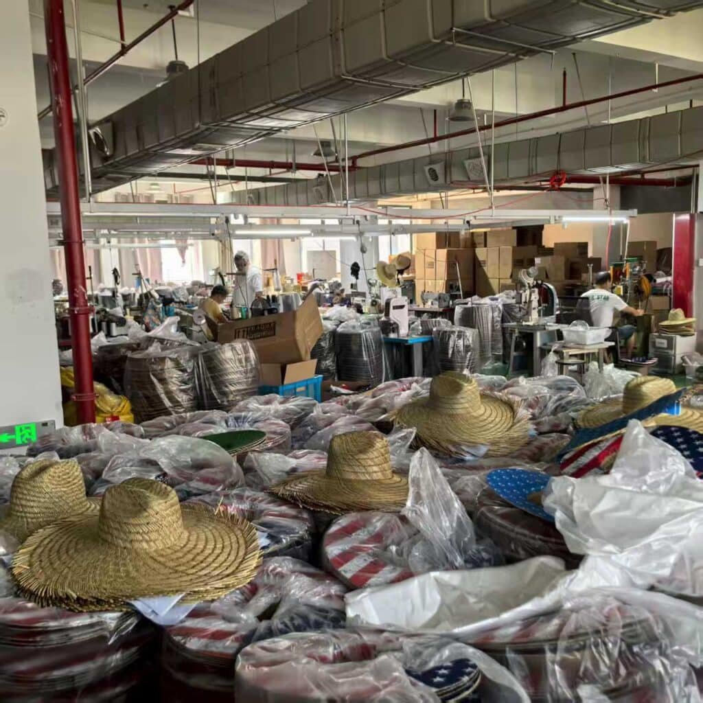 Production workshop filled with packed straw hats and boxes, showing large-scale manufacturing and bulk export preparation.