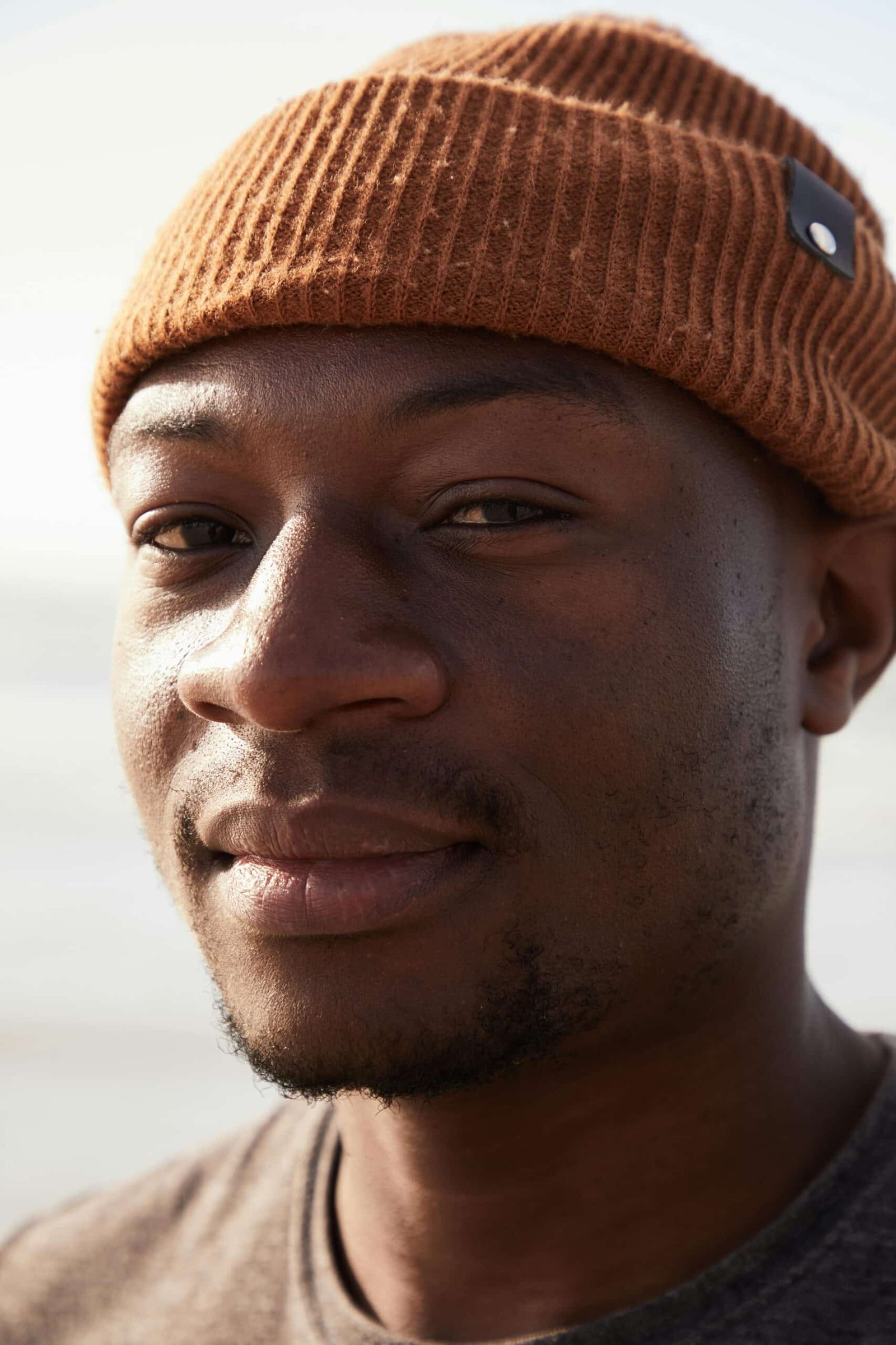 Man wearing rust knit men’s beanie—workwear branding lifestyle shot.