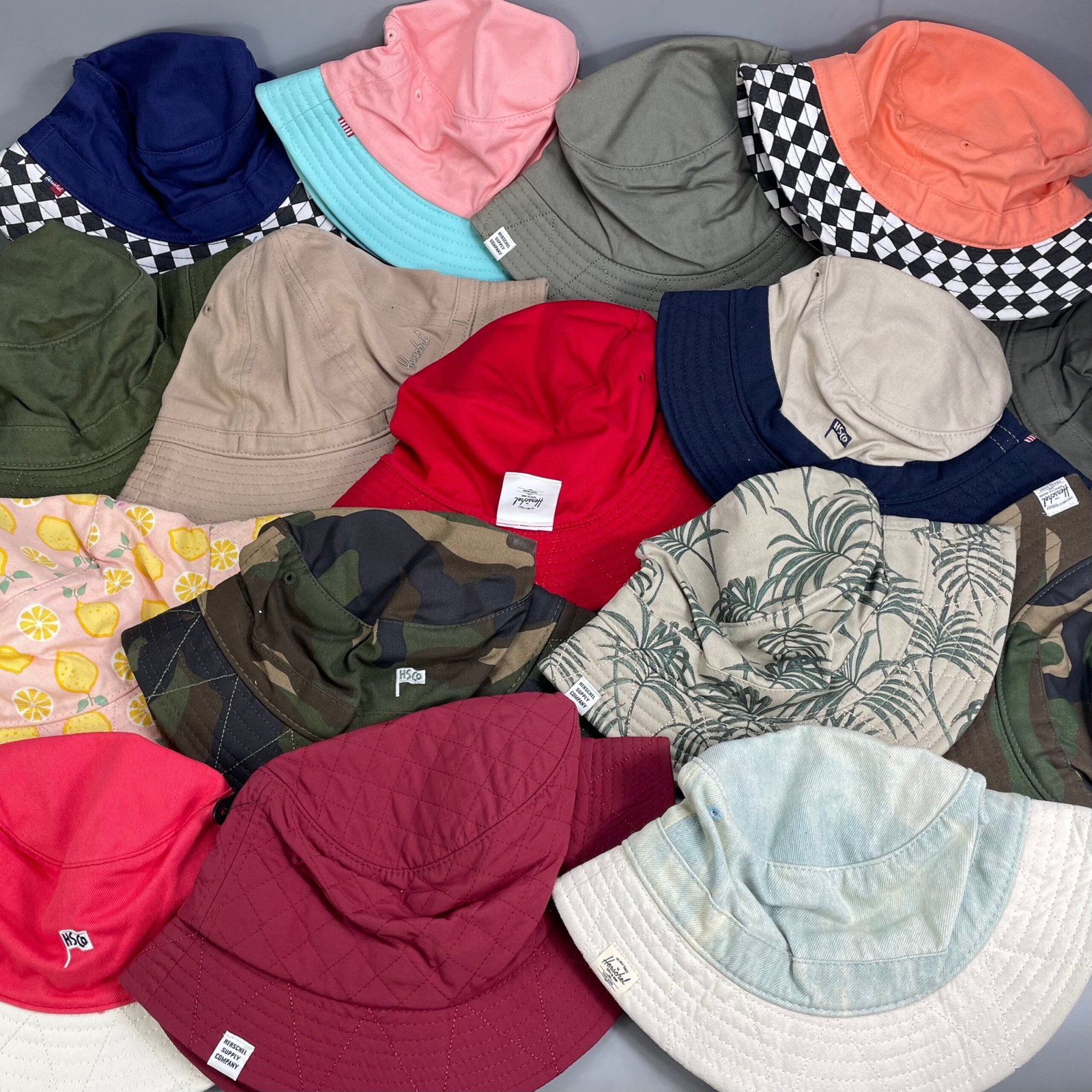 Assorted bucket hats in multiple colours and prints, displaying custom bucket hat options for brands.