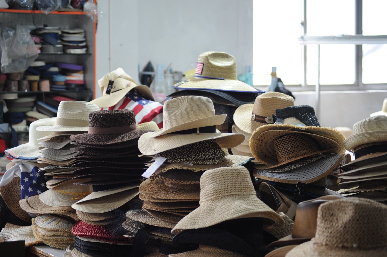 Finished straw hats stacked in factory, including wide brim and lifeguard hat styles